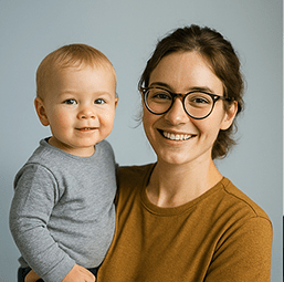 “Mother holding a smiling toddler, both facing the camera in a warmly lit portrait.”